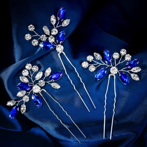 Détail de trois épingles à cheveux argentées avec cristaux bleus et blancs sur soie bleue