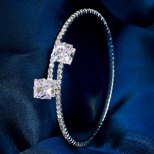 Sparkling silver open bangle with large square zircons on elegant blue silk fabric