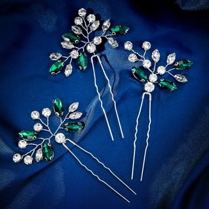 Detailed view of 3-piece silver hair pins with green rhinestones on blue satin