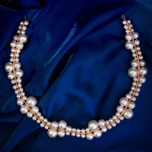 Close-up of handmade bridal hair vine with cream pearls and gold wire on blue silk