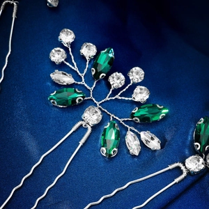 Detailed macro shot of silver bridal hair pin with emerald crystals and rhinestones