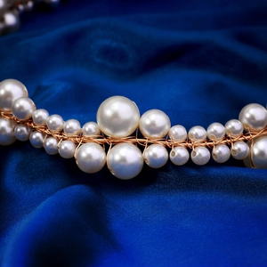 Detailed macro view of hand-woven faux pearls and golden wire on silk background