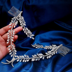 Elegant silver bridal headpiece with rhinestone leaves held against blue silk fabric
