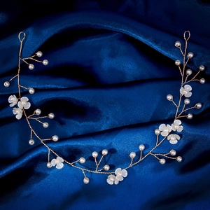 Détail d'un bandeau de mariée fait main avec fil doré, perles blanches et fleurs
