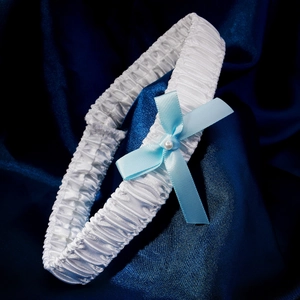 Detail view of bridal garter with white ruffled ribbon and light blue satin bow with pearl