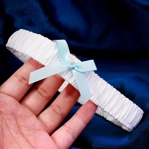 Elegant white lace bridal garter with a light blue bow and pearl accent for weddings