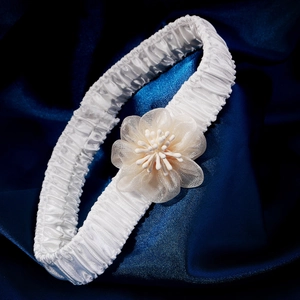 Elegant white lace wedding garter with champagne mesh flower on dark blue satin background