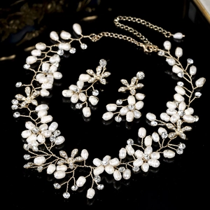 Handmade bridal jewelry set with pearl necklace and vine earrings on black background