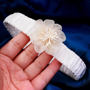 Detail of white lace bridal garter with delicate layered mesh flower and satin texture