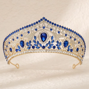 Detail of royal gold tiara with large teardrop blue crystal and symmetric rhinestones