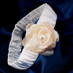 Close-up of bridal leg garter with cream fabric rose and faux pearl on blue silk