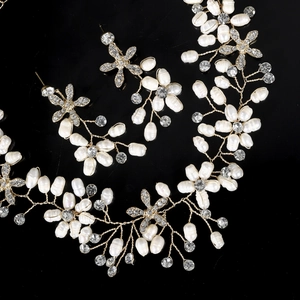 Close-up of handmade pearl and rhinestone bridal jewelry set with golden wire weave