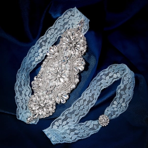 Light blue lace bridal garter set with crystal rhinestones and pearls on blue satin