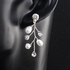 Detail of silver branch earrings with white pearls and crystals on a black display
