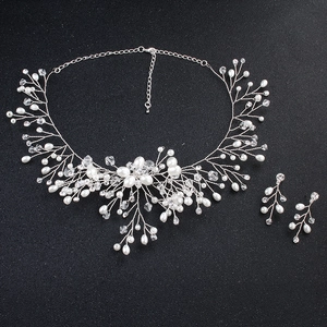 Macro shot of handmade pearl and crystal bridal jewelry set with floral wire design