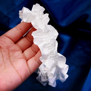 Detailed view of white pleated bridal garter made of smooth satin with elastic lace bow