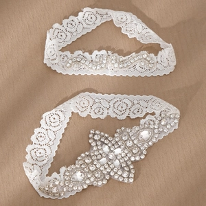 Detailed view of hand-stitched white lace wedding garter set with pearls and rhinestones