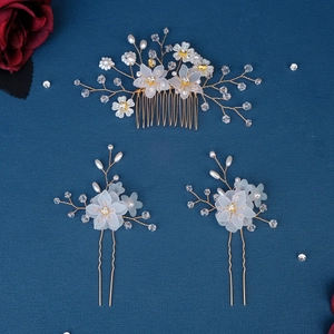Detail of bridal hair comb set with white flowers and pearls on blue background