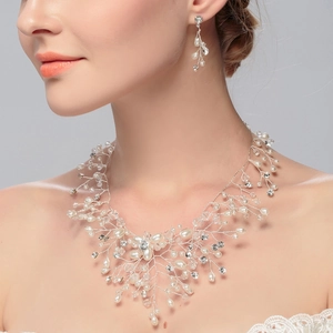 Detailed close-up of bridal pearl necklace and earrings set with crystal vine design