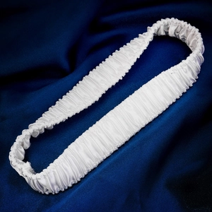 Detailed close-up of white pleated elastic lace bridal garter on blue satin background