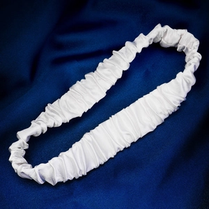 Close-up of white ruched bridal garter with satin finish on elegant navy blue silk