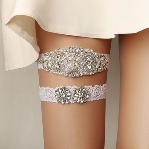Detailed view of hand-sewn bridal garter set with pearls and rhinestones on lace