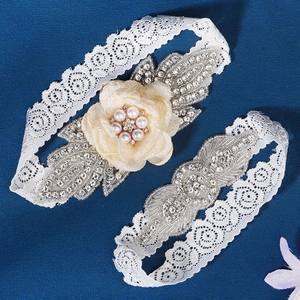 Close-up of bridal garter set featuring white floral lace, rhinestones, and pearls