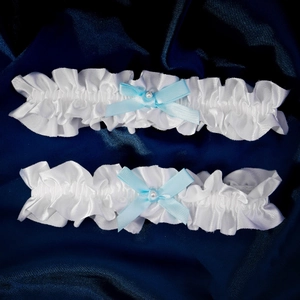 Elegant bridal lace garters set with blue bows and pearls on dark satin background