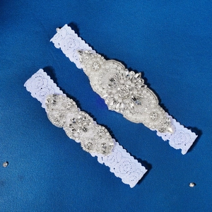 Detailed macro view of white bridal lace garters with luxury rhinestone and pearl embellishments