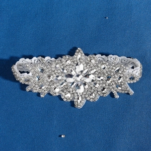 Macro shot of silver wedding garter featuring sparkling crystals and white lace detail