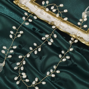 Detailed macro view of handmade gold bridal hair vine with white pearls and silk ribbon