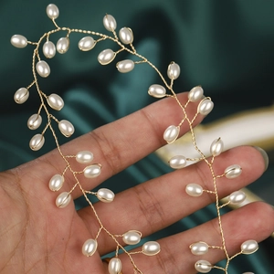 Detail of handcrafted wedding belt with pearls and gold wire on green silk fabric