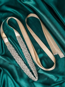 Close-up of handmade bridal belt with sparkling rhinestones and champagne satin ribbon