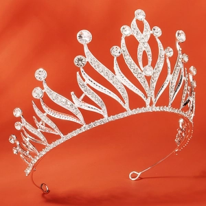 Detailed view of silver alloy bridal crown with sparkling rhinestones on orange background