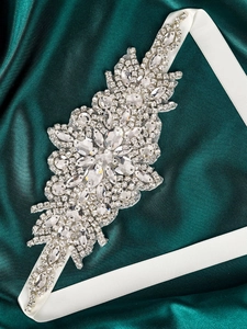 Detail view of handmade bridal belt with crystal flowers on a white satin ribbon