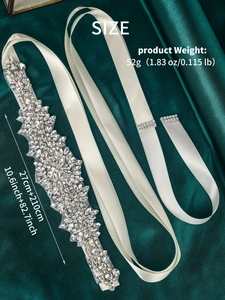 Macro shot of hand-sewn silver rhinestones on ivory satin sash for bridal wedding dresses