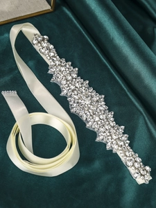 Close-up of hand-sewn rhinestones on a satin bridal belt with elegant sparkle