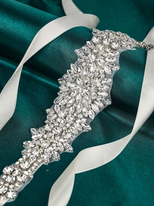 Macro detail of hand-stitched crystal bridal belt with silver rhinestones and white ribbon
