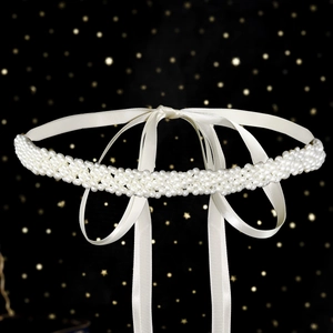 Detailed macro of handmade crystal rhinestone and pearl bridal belt with white silk ribbon