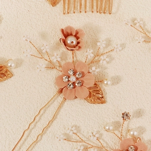 Detail of pink fabric flower hair pin with gold leaves, pearls, and rhinestones