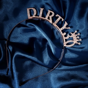Close-up of rose gold Dirty 30 tiara with white rhinestones on blue satin background
