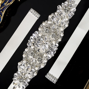 Close-up of handmade bridal sash featuring sparkling crystals and white pearls on satin ribbon