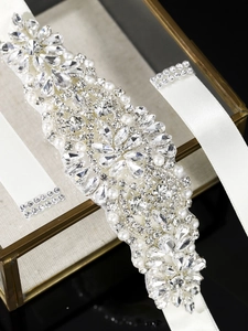Close-up of hand-sewn rhinestones and white pearls on a bridal gown sash belt