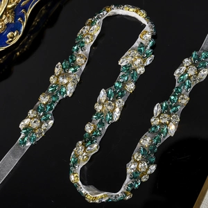 Macro shot of hand-sewn green and white crystal rhinestones on sheer bridal belt mesh