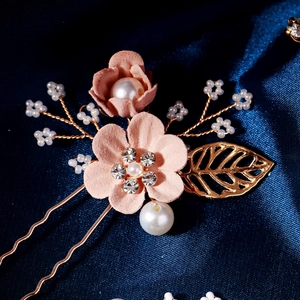 Detailed close-up of pink velvet flower hairpins with pearls, rhinestones and golden leaves