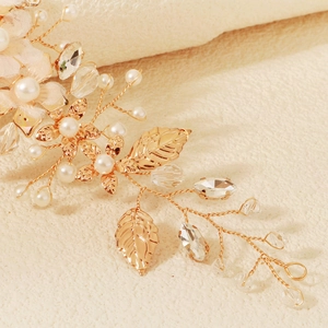 Detail of handcrafted gold floral hair pin with white pearls and sparkling crystals