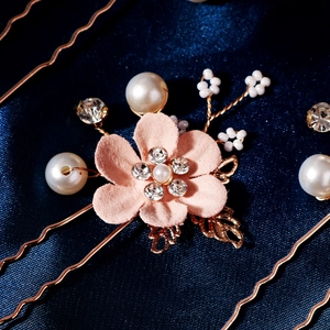 Close-up of pink matte flowers and white pearls on gold bridal hair pins detail