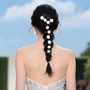 Detail of white polymer clay flower hair pins with pearl centers in a bridal hairstyle