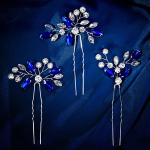 Gros plan détaillé de trois épingles à cheveux en strass bleu roi sur tissu en soie