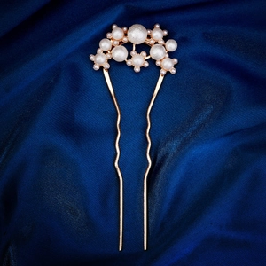 U-shaped golden hair pin with white pearls on a dark blue satin fabric background